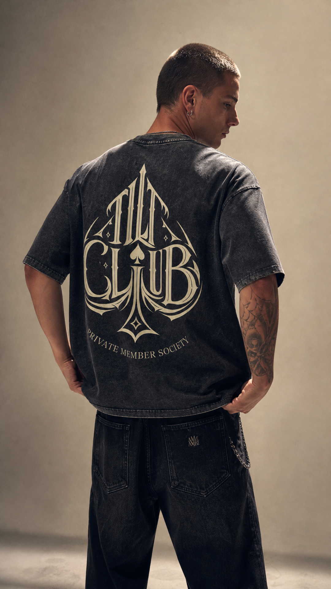 Model wearing the back design of the Spyre snow washed tee, white studio, Tilted Spades