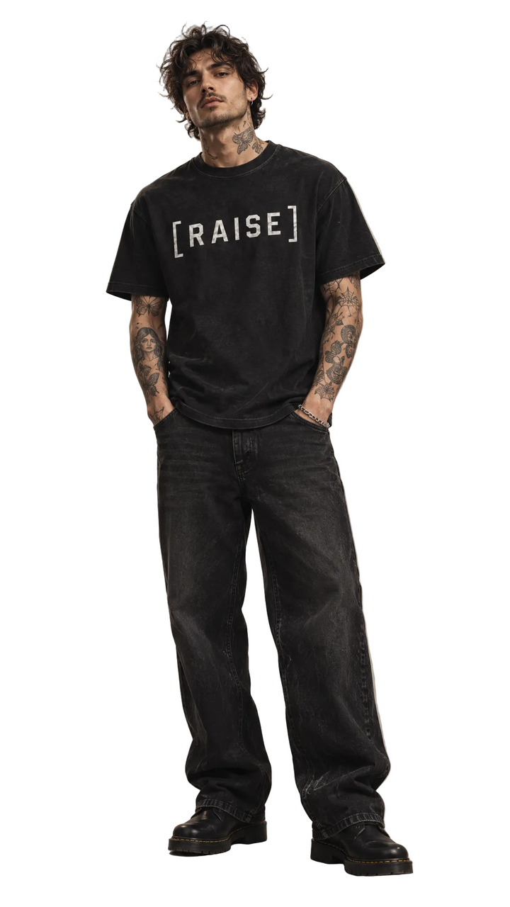 Male model with tattoos wearing the Raise The Stakes tee, white studio, Tilted Spades